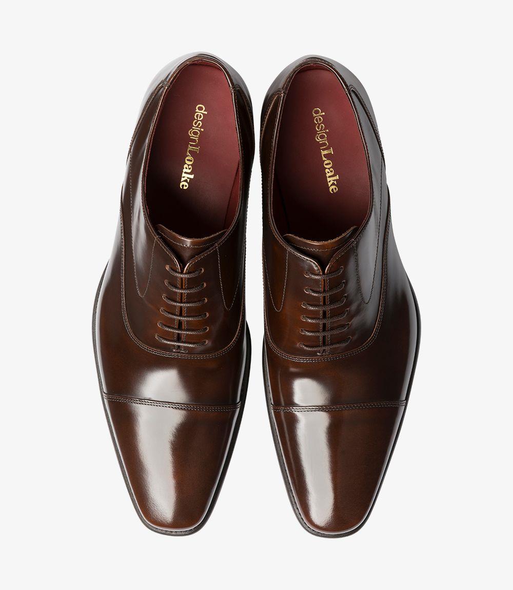 From above, the Loake Sharp Dark Brown Oxford presents a refined and polished appearance. The symmetrical lace-up design draws the eye, with neatly arranged laces and a gently rounded toe. The dark brown leather shines, showcasing its high-quality finish, while the toe cap adds an element of sophistication. The smooth lines of the upper and the subtle stitching details create an impression of elegance, making this shoe a versatile choice for various formal occasions.